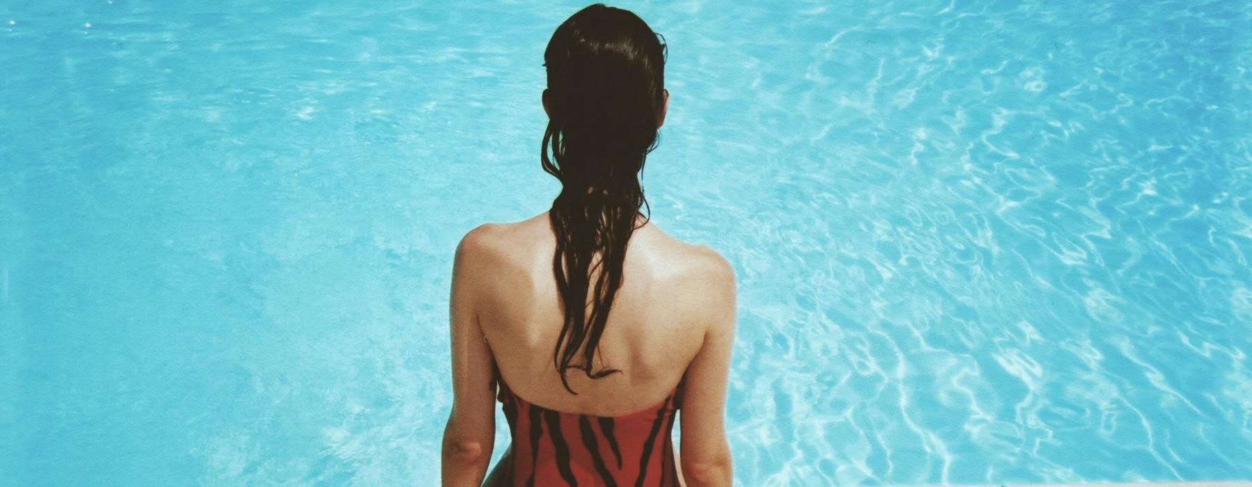 a person sitting on a ledge looking at the water